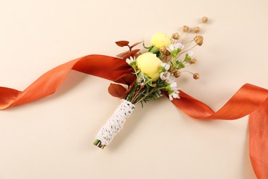 Stylish boutonniere and ribbon on beige background, top view