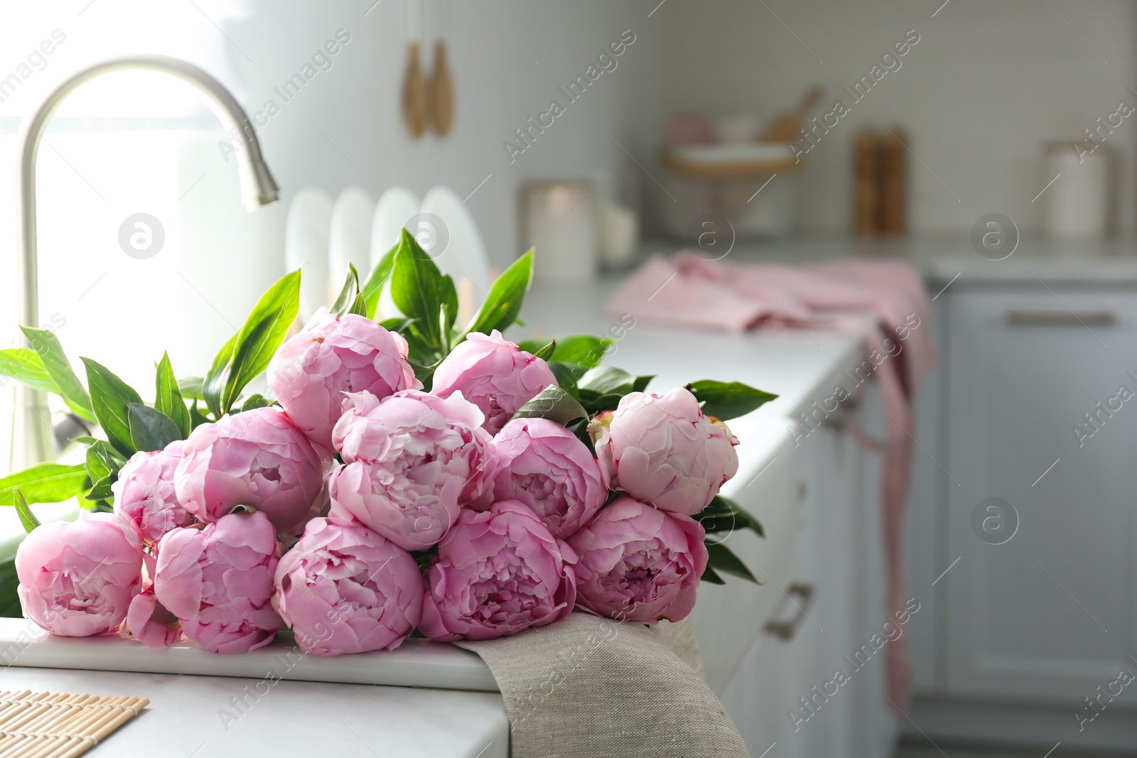 Photo of Bouquet of beautiful pink peonies in kitchen sink