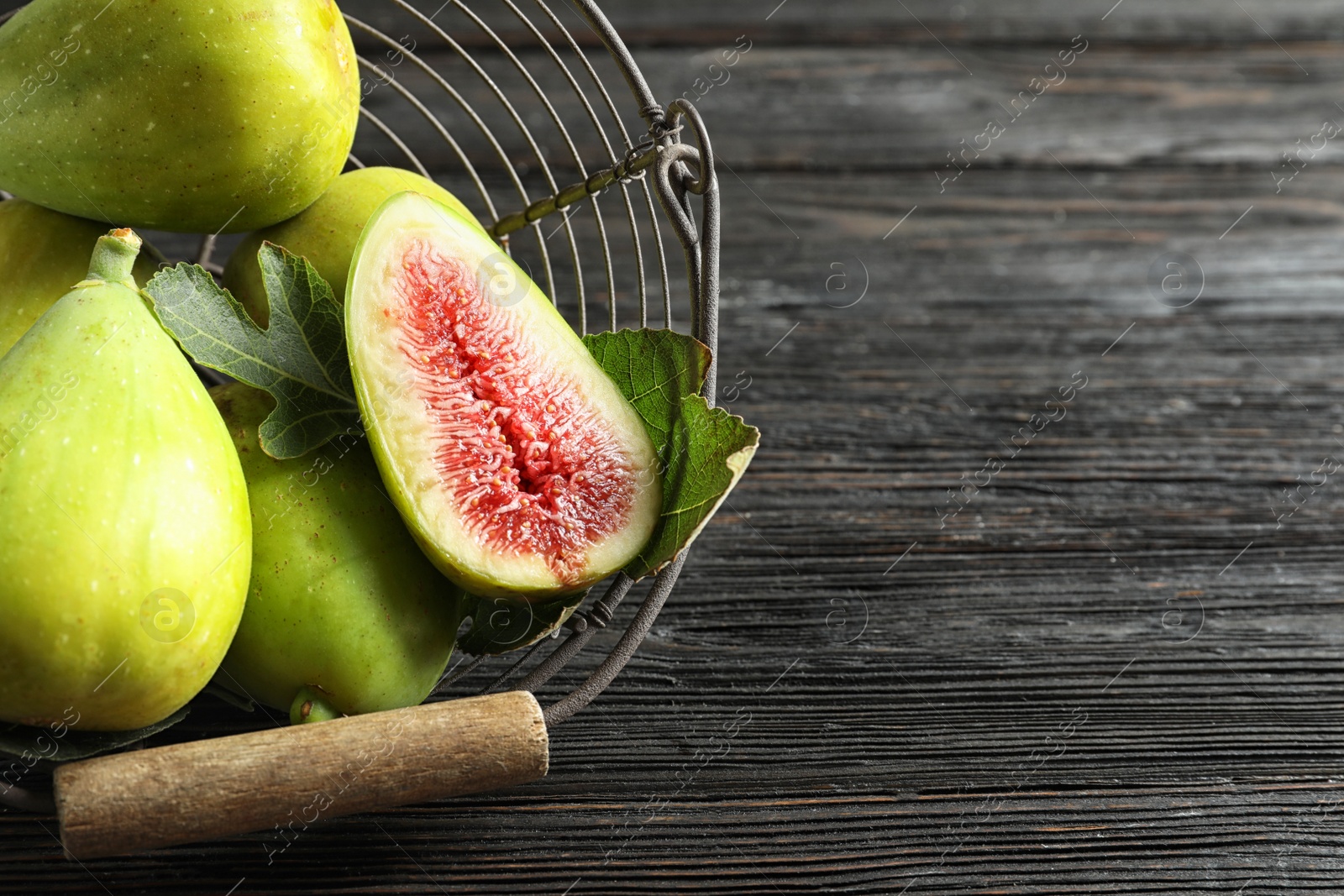 Photo of Fresh ripe figs in basket on wooden table, top view. Space for text