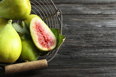 Photo of Fresh ripe figs in basket on wooden table, top view. Space for text