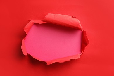 Photo of Hole in red paper on pink background