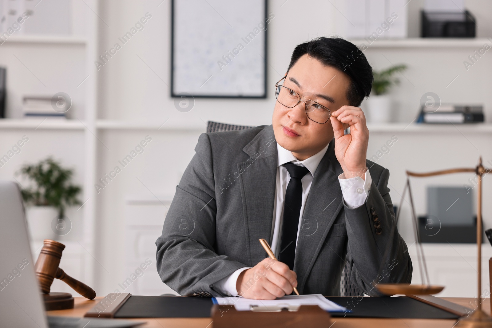 Photo of Notary writing notes at wooden table in office