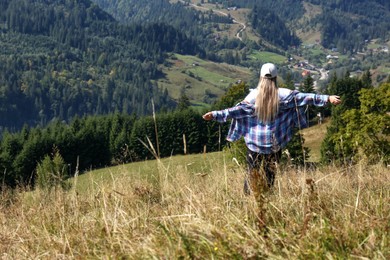 Photo of Woman enjoying picturesque landscape from top of hill, back view. Space for text