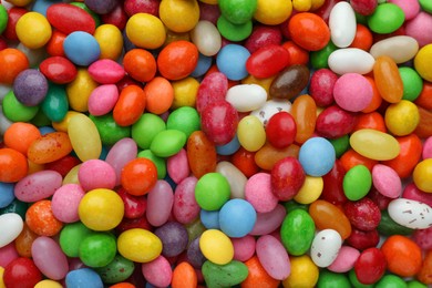 Many tasty colorful dragee candies as background, top view