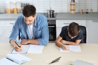 Photo of Dad helping his son with homework in kitchen