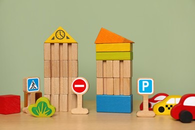 Photo of Set of different wooden toys on table near olive wall. Children's development