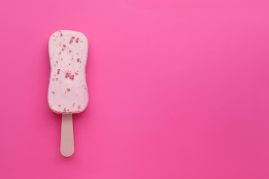 Photo of Delicious glazed ice cream bar on pink background, top view. Space for text