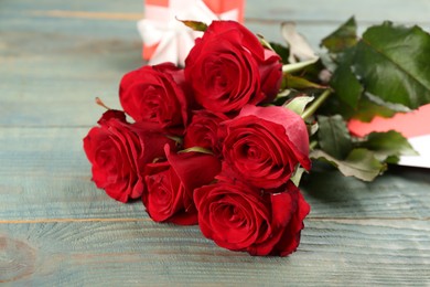 Photo of Beautiful red roses on blue wooden table, closeup. Valentine's Day celebration