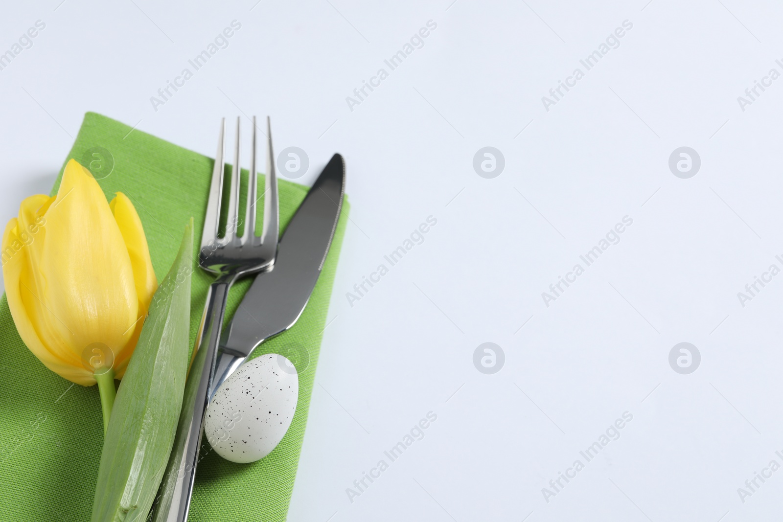 Photo of Cutlery set, Easter egg and tulip on white background, space for text. Festive table setting