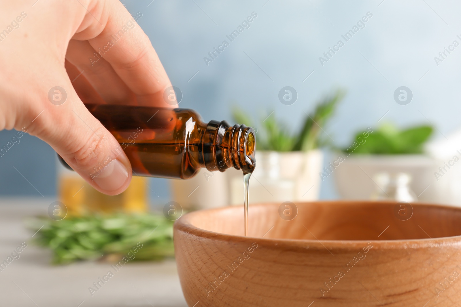 Photo of Woman pouring essential oil into bowl