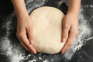 Photo of Female baker preparing bread dough at grey table, top view