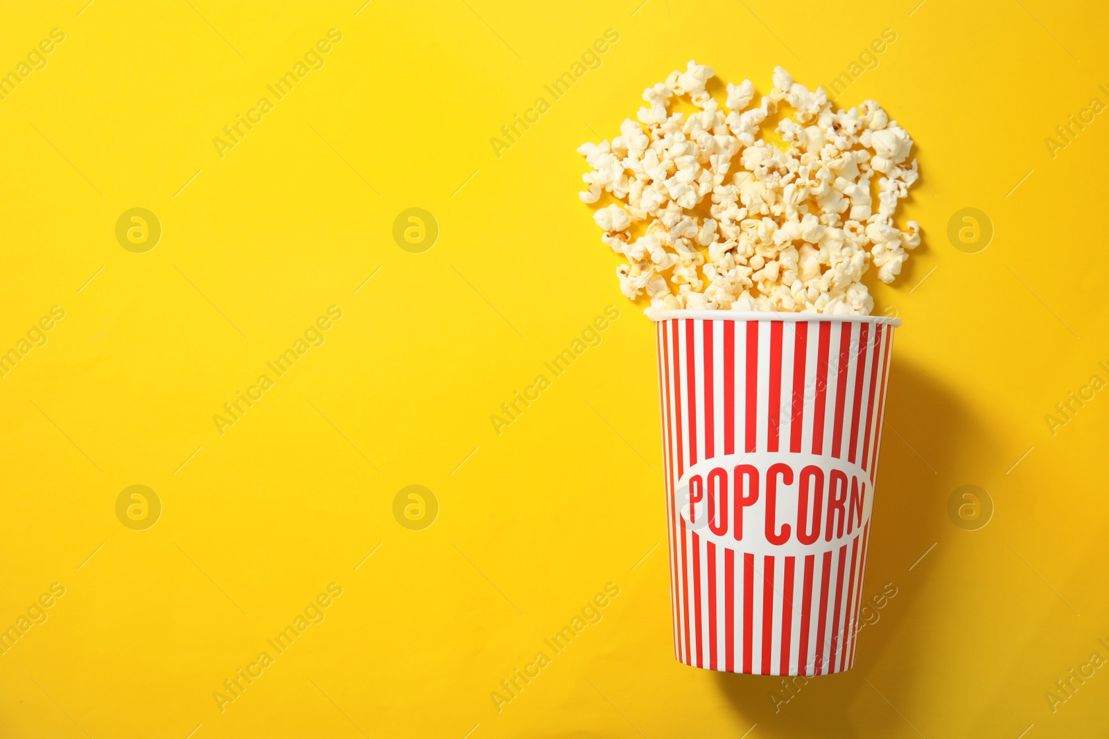 Photo of Fresh tasty popcorn and cup on color background, top view with space for text. Cinema snack