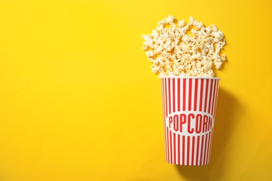 Fresh tasty popcorn and cup on color background, top view with space for text. Cinema snack