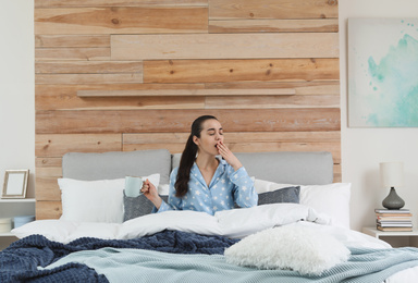 Photo of Woman awakening in large bed at home. Elegant interior