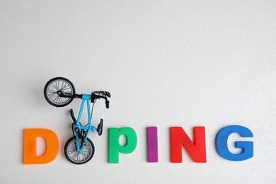 Word Doping and bicycle model on white table, flat lay. Space for text