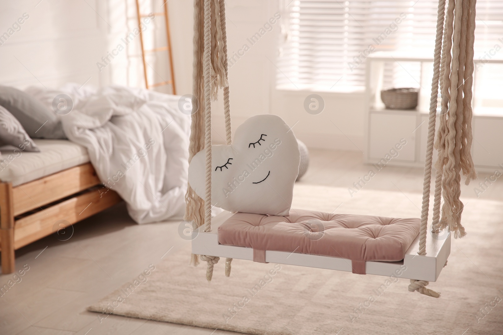 Photo of Beautiful swing with toy heart in bedroom. Stylish interior design