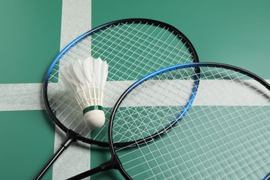 Feather badminton shuttlecock and rackets on green table, closeup