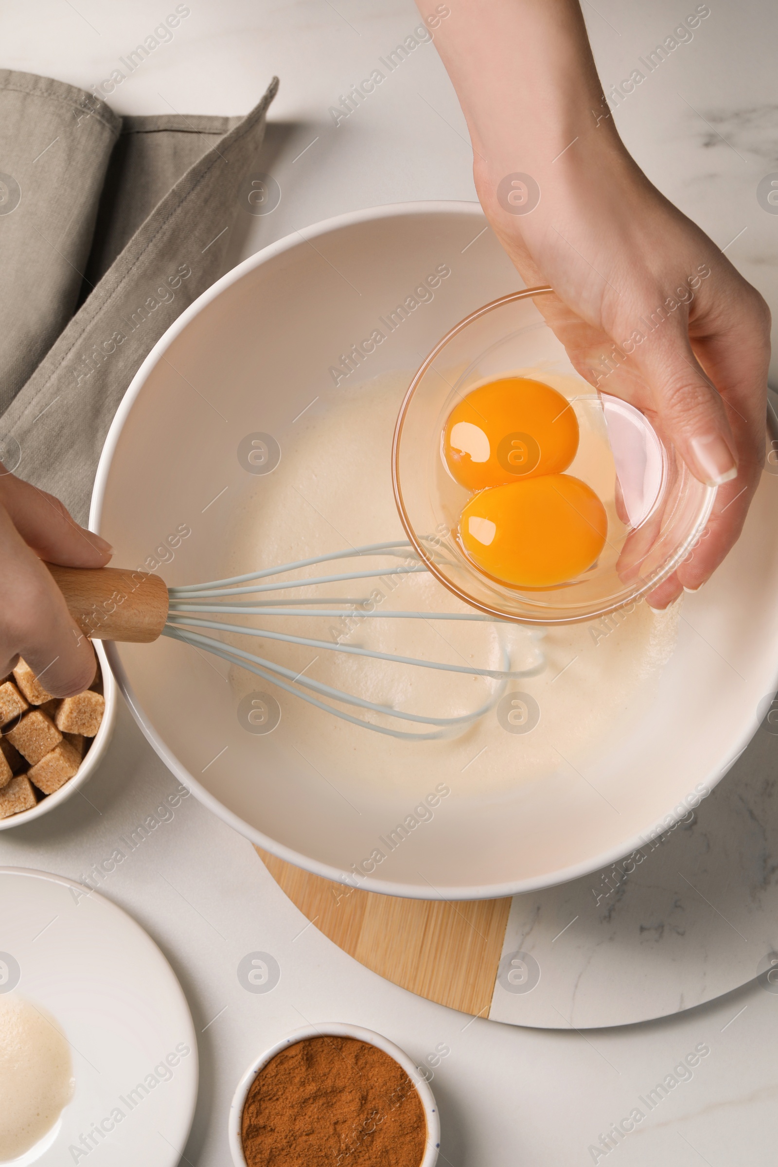 Photo of Woman mixing ingredients at white marble table, top view. Cooking delicious eggnog