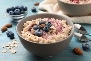 Photo of Tasty oatmeal porridge with toppings on light blue wooden table