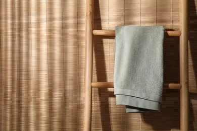 Photo of Green terry towel on wooden ladder indoors, space for text