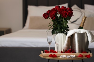 Honeymoon. Sparkling wine, glasses and bouquet of roses on wooden table in room. Space for text