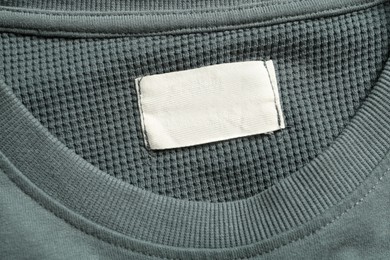 Photo of Blank clothing label on grey sweater, top view