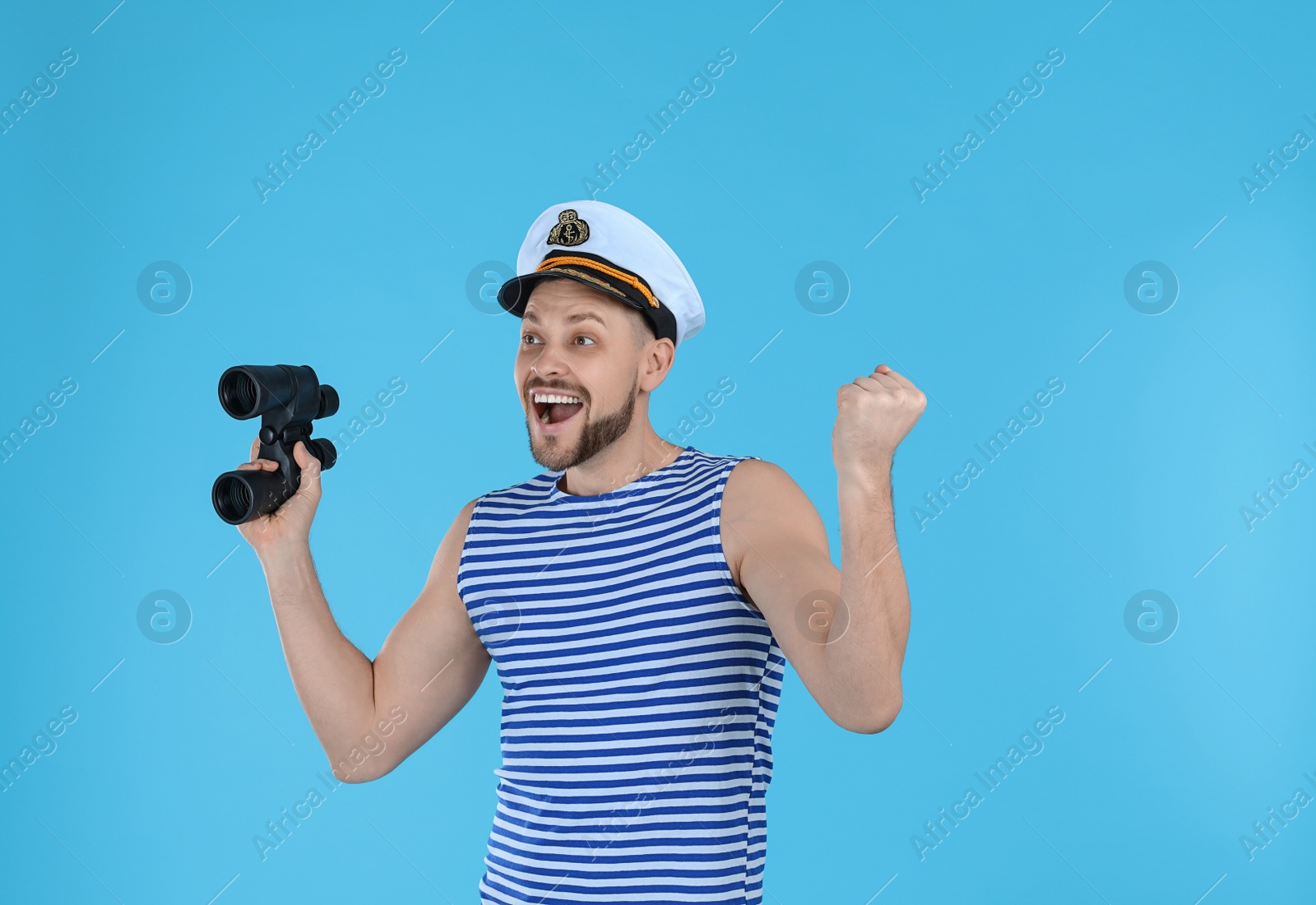 Photo of Happy sailor with binoculars on light blue background