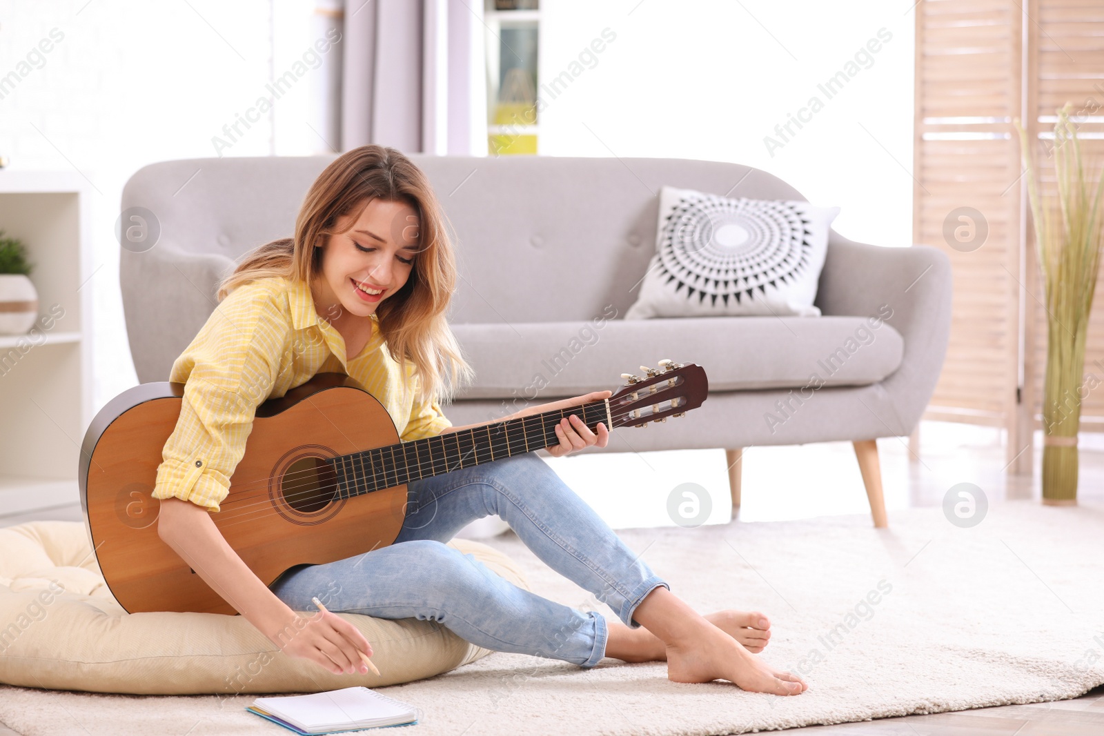 Photo of Young woman with acoustic guitar composing song in living room. Space for text