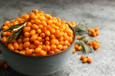 Photo of Fresh ripe sea buckthorn in bowl on grey table, closeup