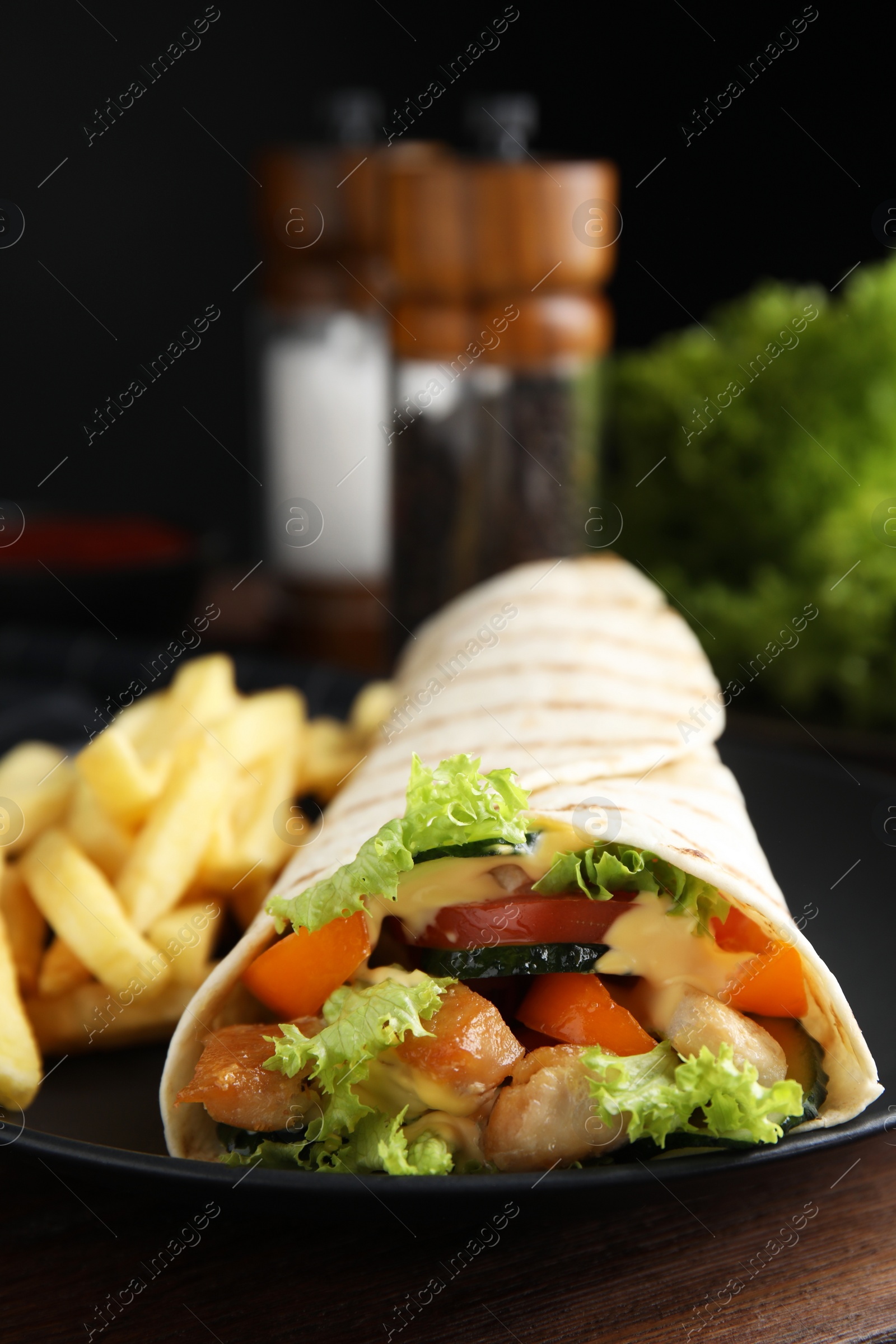 Photo of Delicious chicken shawarma and French fries on wooden table, closeup
