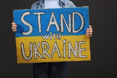 Boy holding poster Stand with Ukraine against grey background, closeup