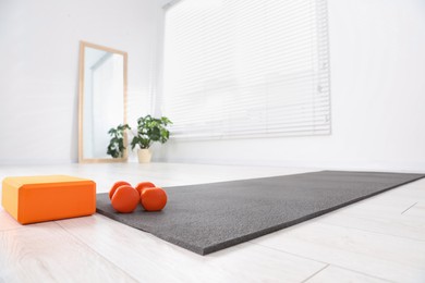 Photo of Exercise mat, yoga block and dumbbells at home, low angle view