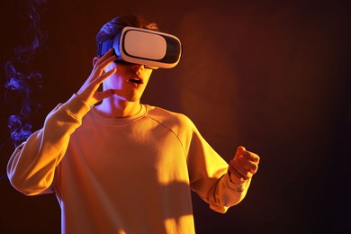 Photo of Young man with virtual reality headset on brown background