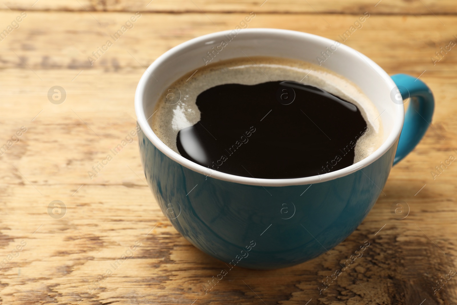 Photo of Cup of aromatic coffee on wooden table, closeup. Space for text