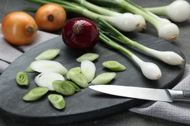 Board with different kinds and knife of onions on grey table, closeup