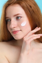 Photo of Beautiful woman with freckles and cream on her face, closeup