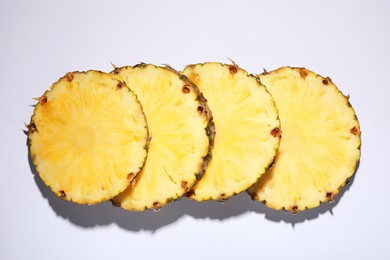 Photo of Slices of tasty ripe pineapple on white background, flat lay