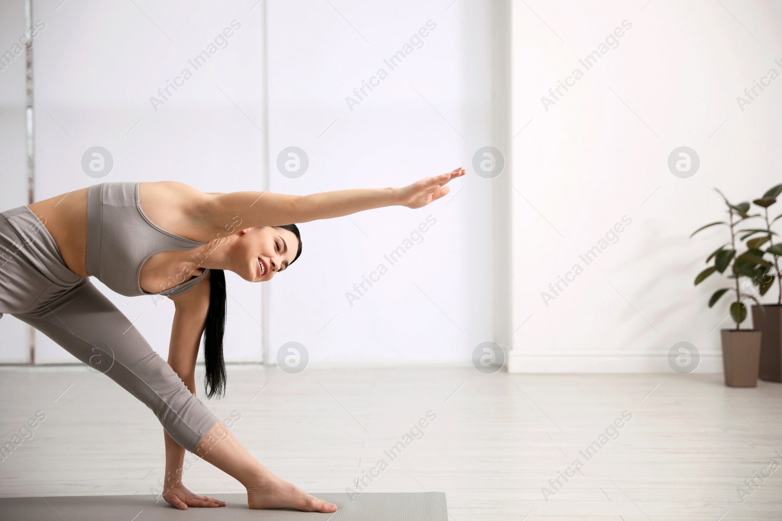 Photo of Young woman practicing triangle asana in yoga studio. Utthita Trikonasana pose