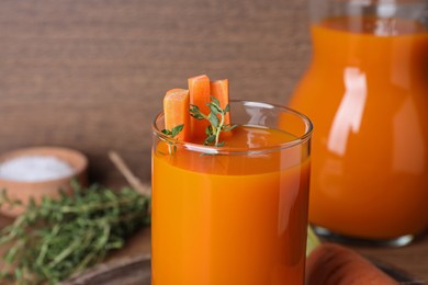 Photo of Freshly made carrot juice in glass on table, closeup