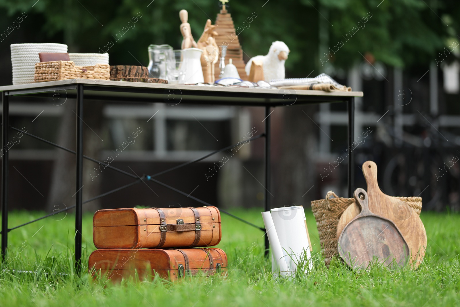 Photo of Table with many different items on grass in yard. Garage sale