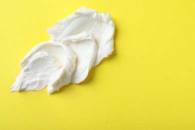 Photo of Smear of delicious cream cheese on yellow background, top view. Space for text