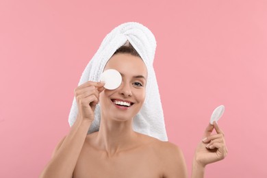 Photo of Smiling woman removing makeup with cotton pads on pink background