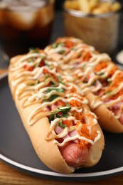 Delicious hot dogs with bacon, carrot and parsley on table, closeup