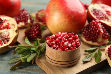 Photo of Delicious ripe pomegranate kernels in bowl on wooden board, closeup