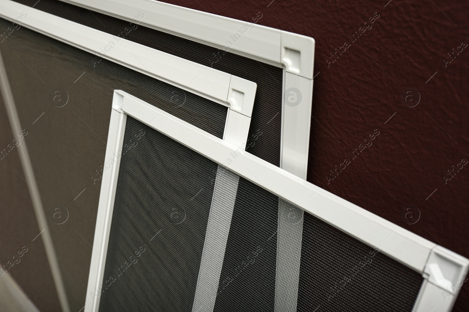 Photo of Set of window screens near brown wall, closeup