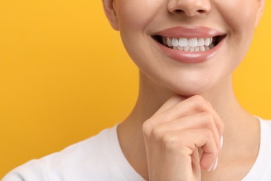 Photo of Woman with clean teeth smiling on yellow background, closeup. Space for text