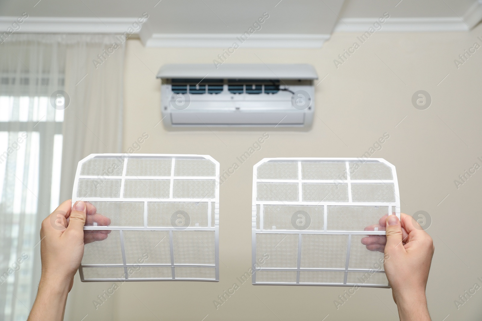 Photo of Man holding filters of air conditioner at home, closeup