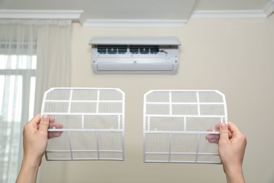 Photo of Man holding filters of air conditioner at home, closeup