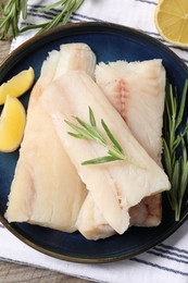 Pieces of raw cod fish, rosemary and lemon on table, top view