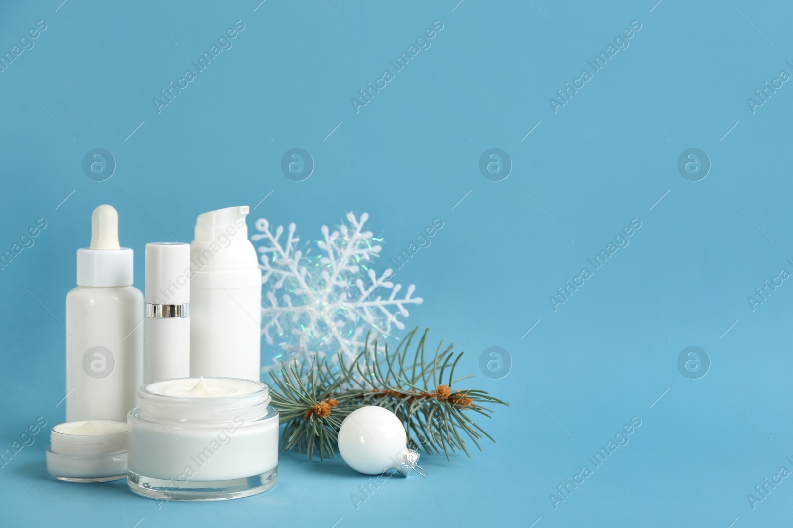 Photo of Beautiful composition with cosmetic products on light blue background, space for text. Winter care